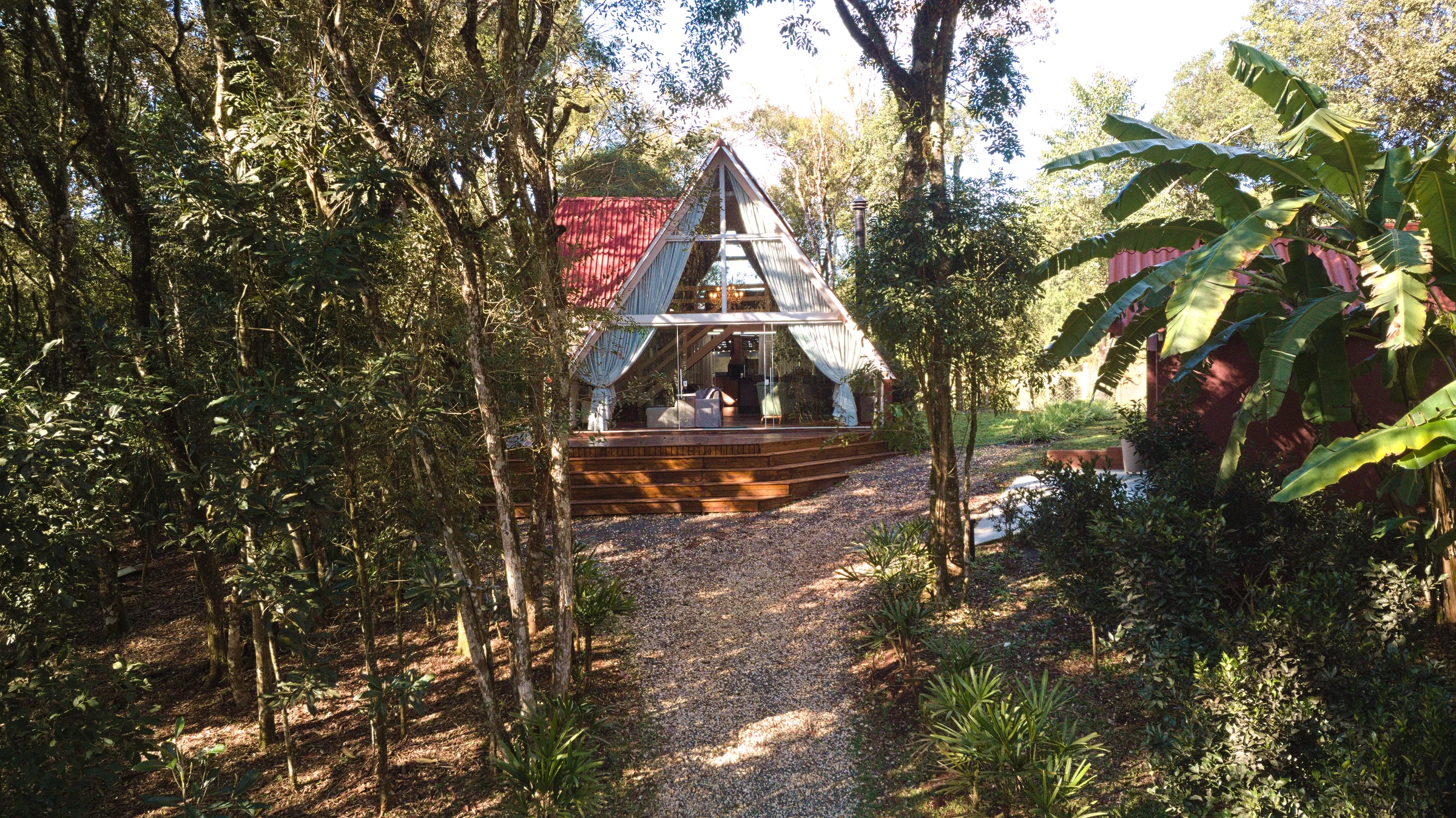 Chalé A-Frame visto pelo acesso entre árvores